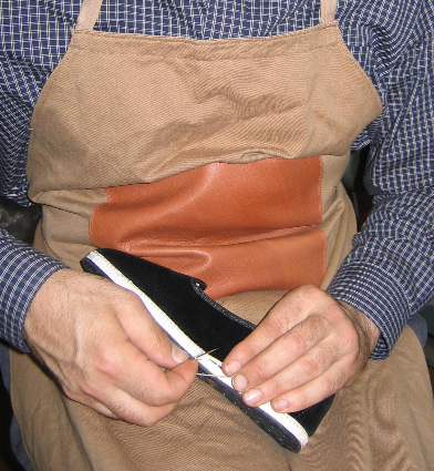 An artisan hand-stitching a velvet Friulana